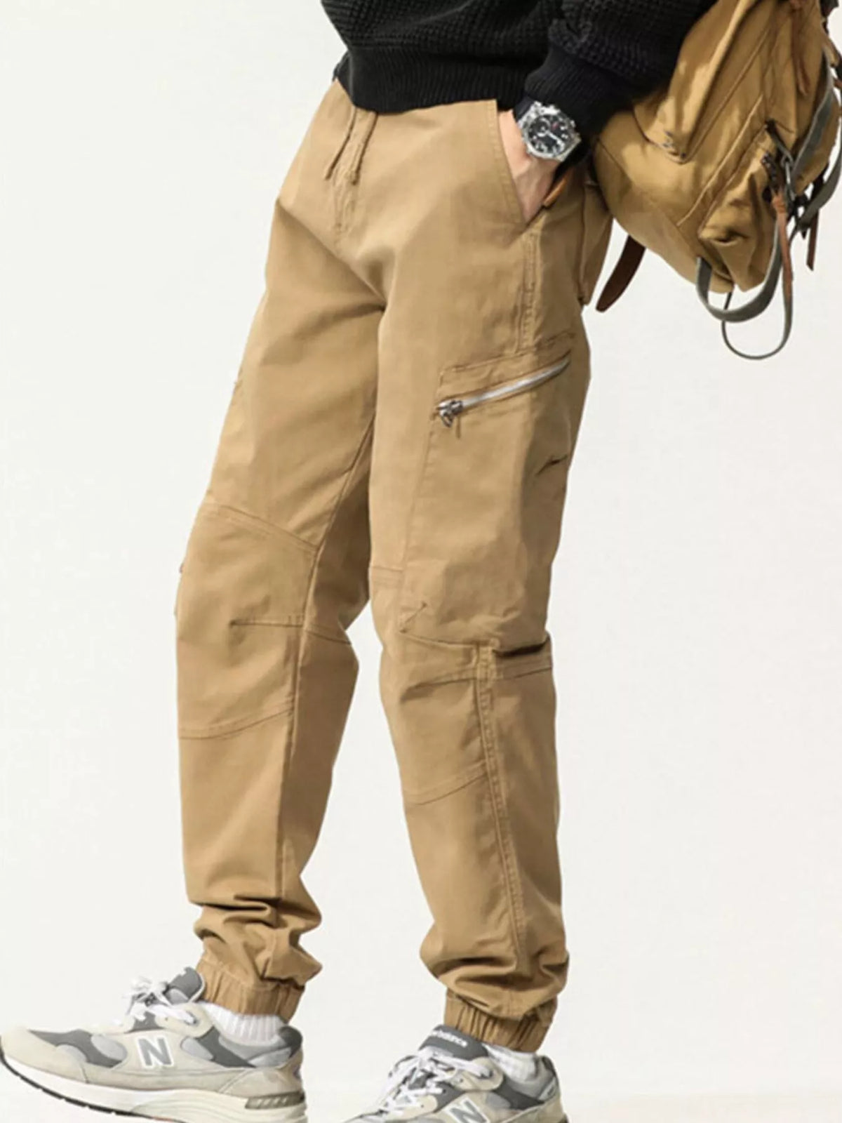 Khaki cargo trousers shown from an angled front view with zip thigh pockets and gathered cuffs; bag and styling items are not included.