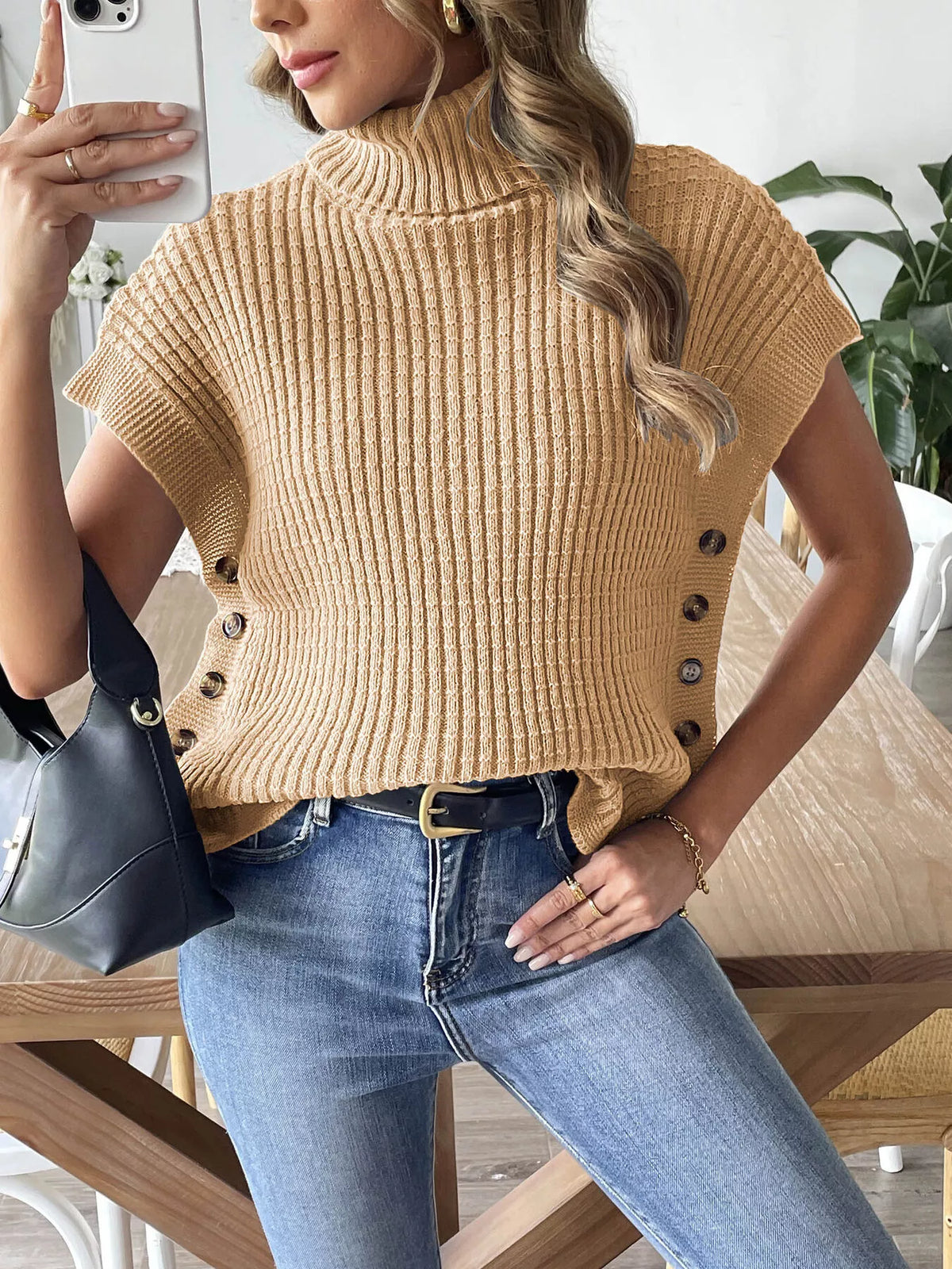 Camel ribbed turtleneck sweater vest with side buttons, styled tucked at the waist; jeans and bag not included.