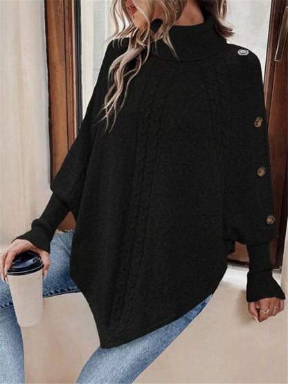 Black cable-knit turtleneck cape sweater. Front three-quarter view, model in blue jeans. Styling accessories are not included.