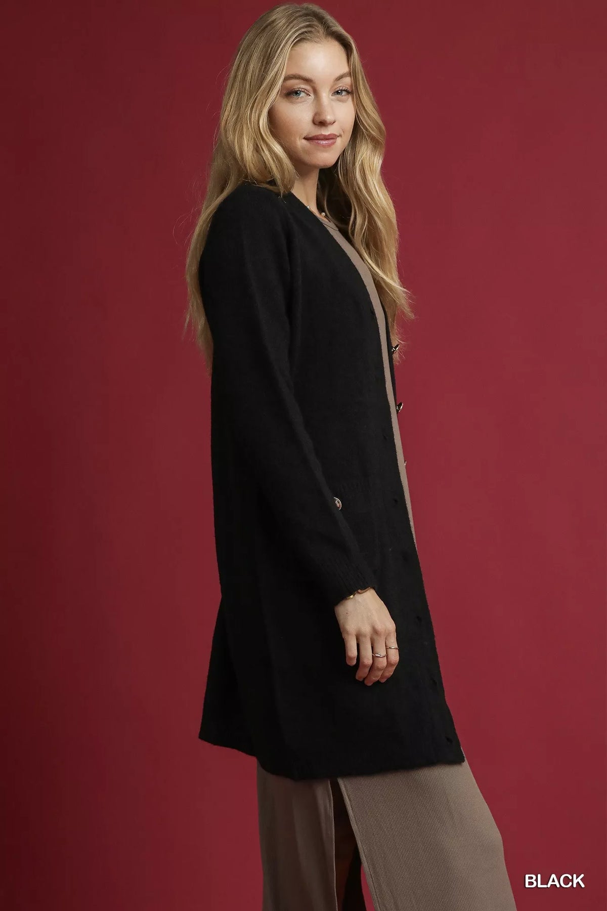 Side view of black Umgee long-sleeve pocket cardigan, styled over a taupe dress; cardigan only.