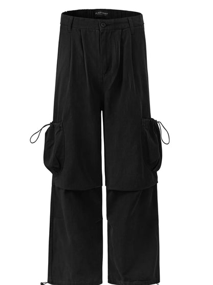 Garment-only front view of black cargo trousers with drawcord side pockets and layered leg panels.