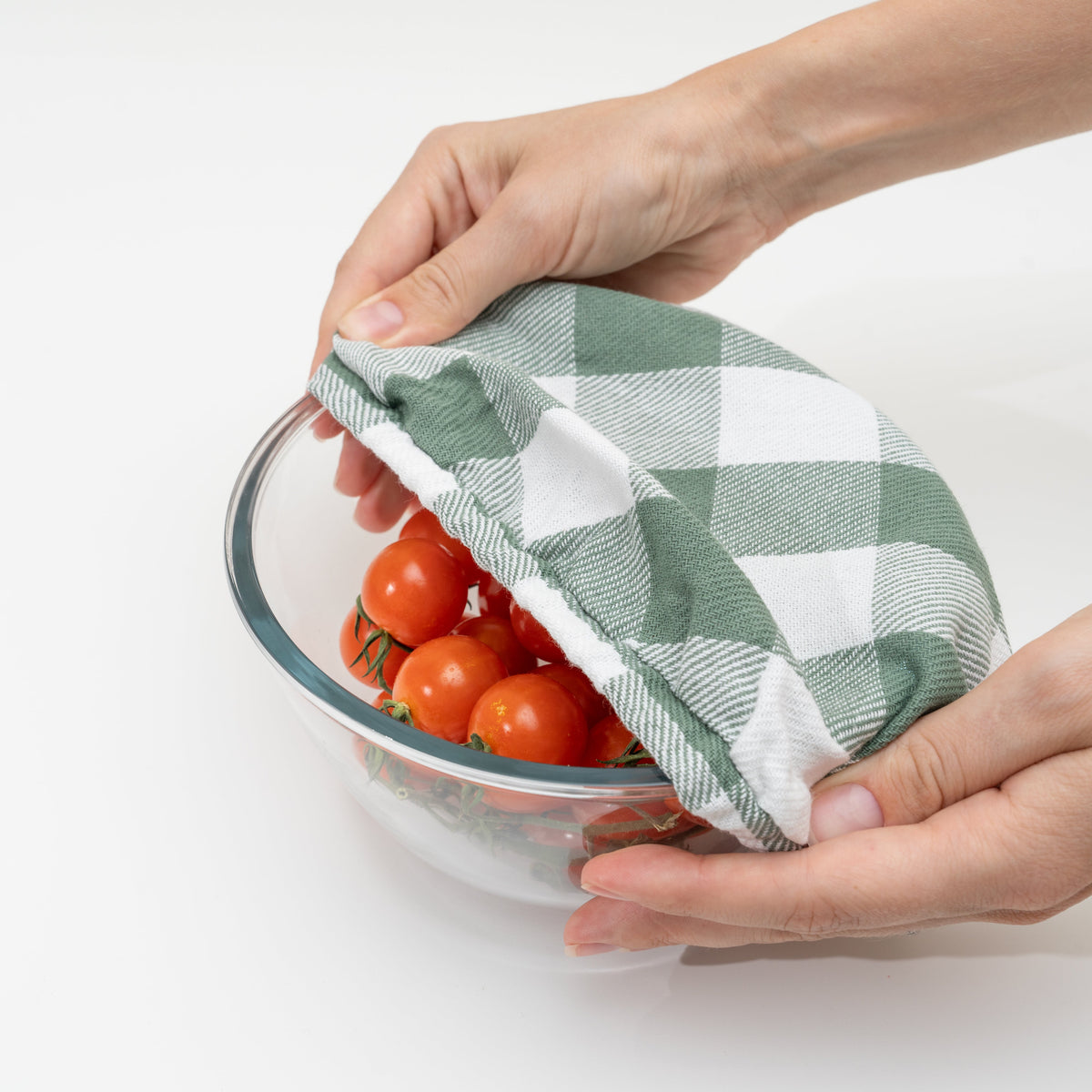 Sage green and white checked elastic cloth cover lifted from a bowl