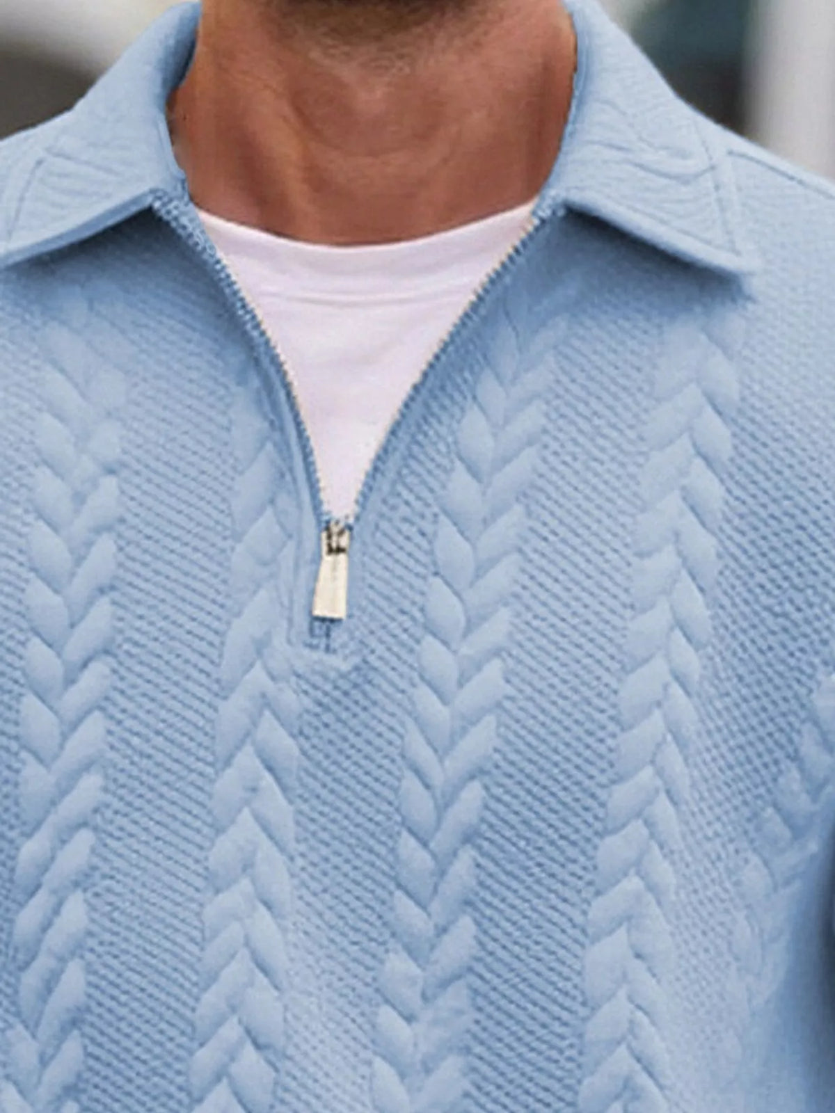 Close view of the light-blue pullover's collar, short zipper and cable-textured knit.