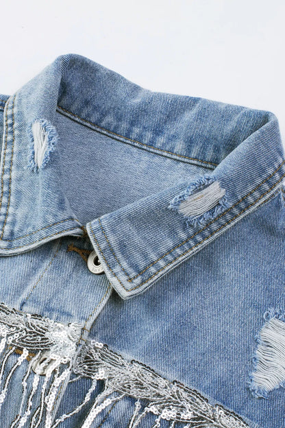 Angled close-up of the denim jacket collar, stitching, distressed patches and top button.