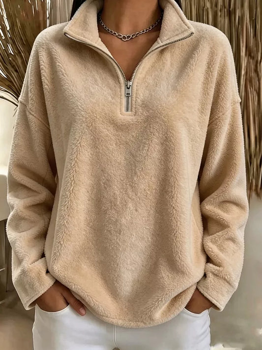 Beige quarter-zip fleece pullover on a model, front view showing a stand collar, long sleeves and curved hem.