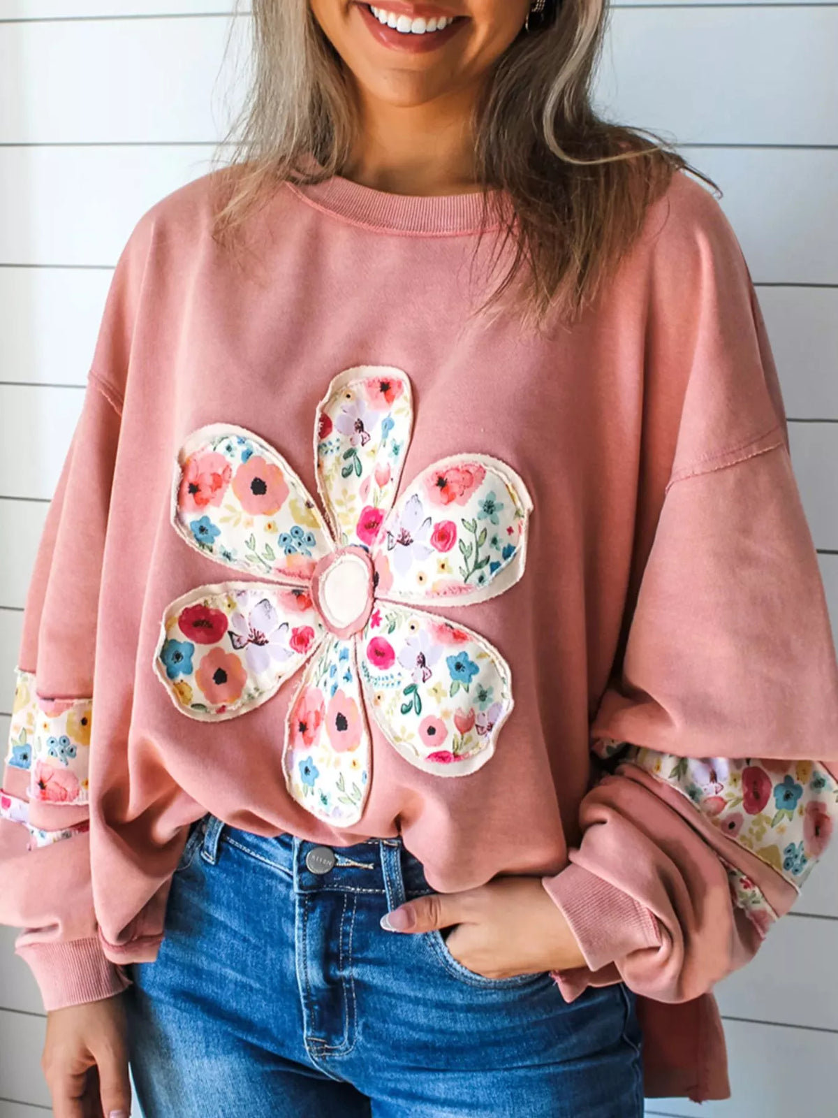 Dusty pink floral applique sweatshirt, front view with round neck and long sleeves. Trousers are styling only.