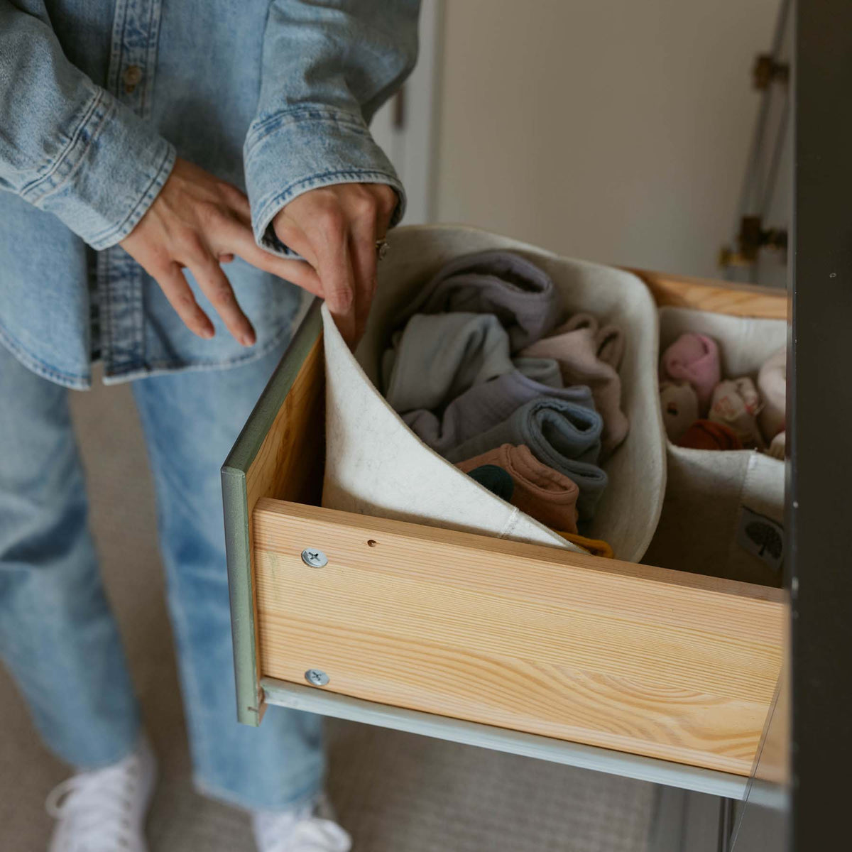A felt organizer holding clothing in an open drawer; clothing and furniture not included.