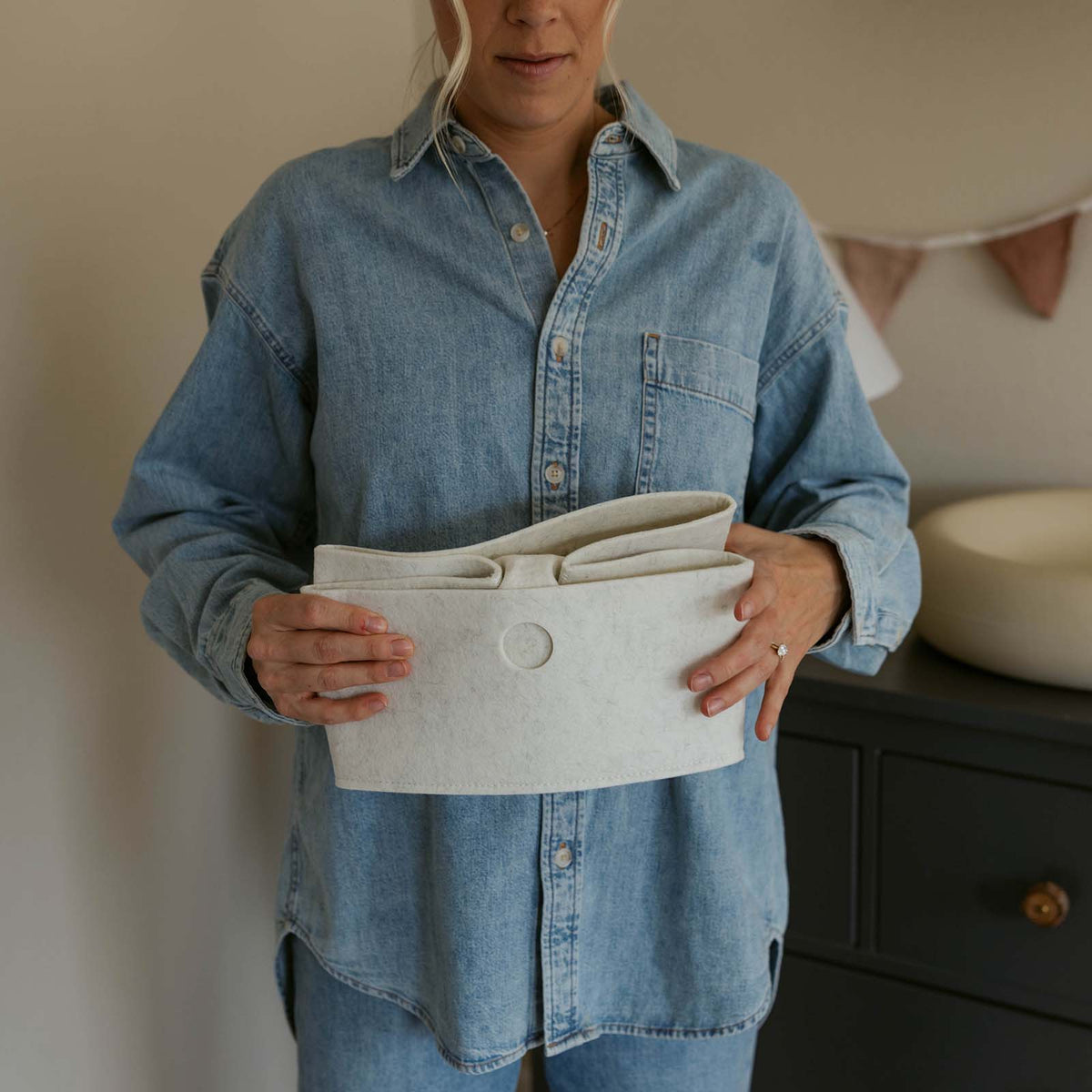 A person folding a felt drawer organizer flat; clothing not included.