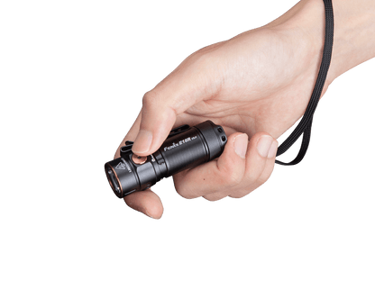 Fenix E18R V2 flashlight held in a hand with lanyard