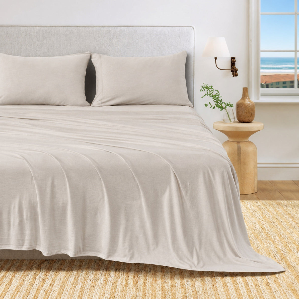 Sand cotton jersey knit sheet set shown on a bed with matching pillowcases in a bright bedroom.