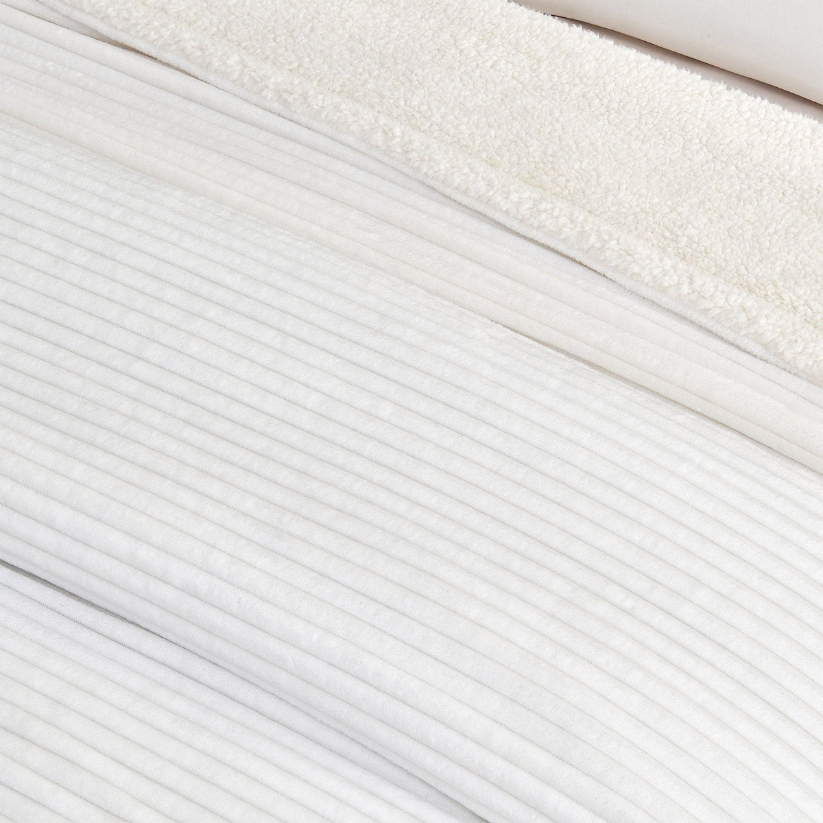 Close-up of the white ribbed face and pale sherpa reverse of the blanket.