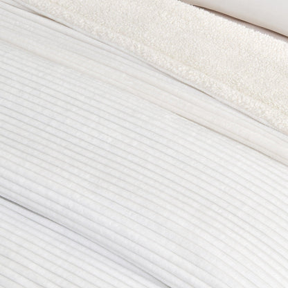 Close-up of the white ribbed face and pale sherpa reverse of the blanket.