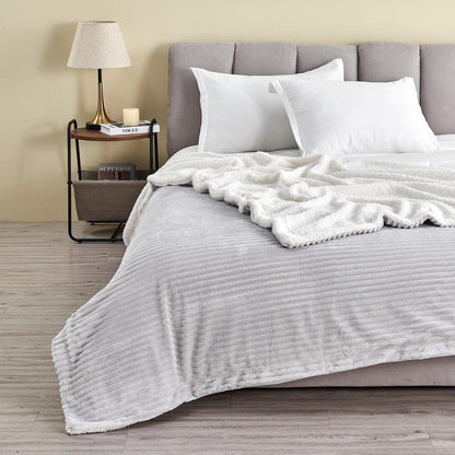 Light Grey ribbed sherpa blanket spread across a bed with its pale reverse folded back; pillows and furnishings are not included.