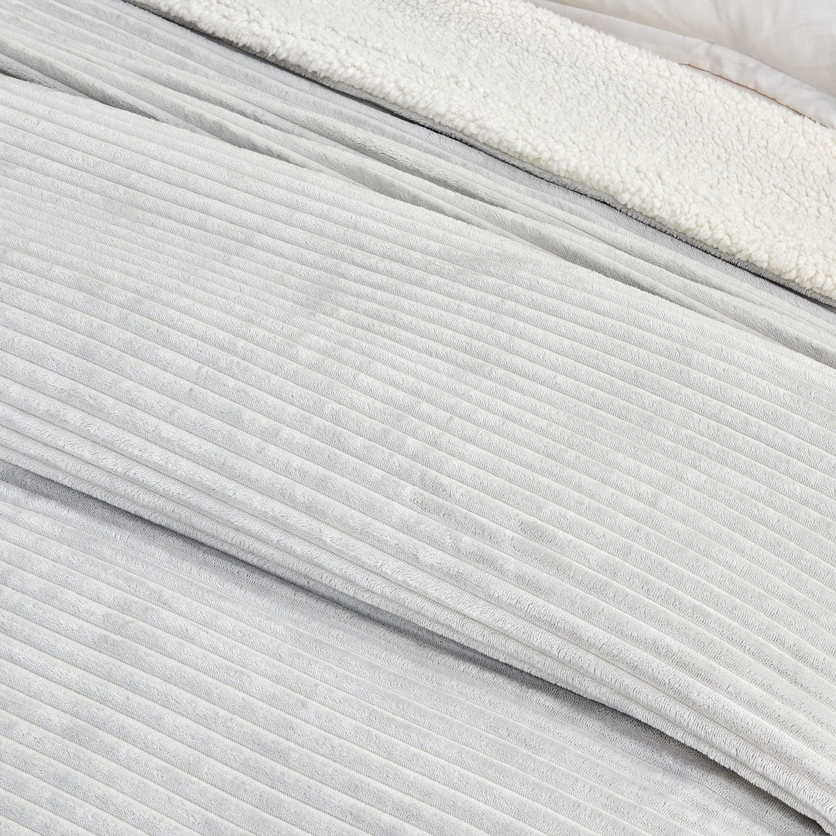 Close-up of the light grey ribbed face and pale sherpa reverse of the blanket.