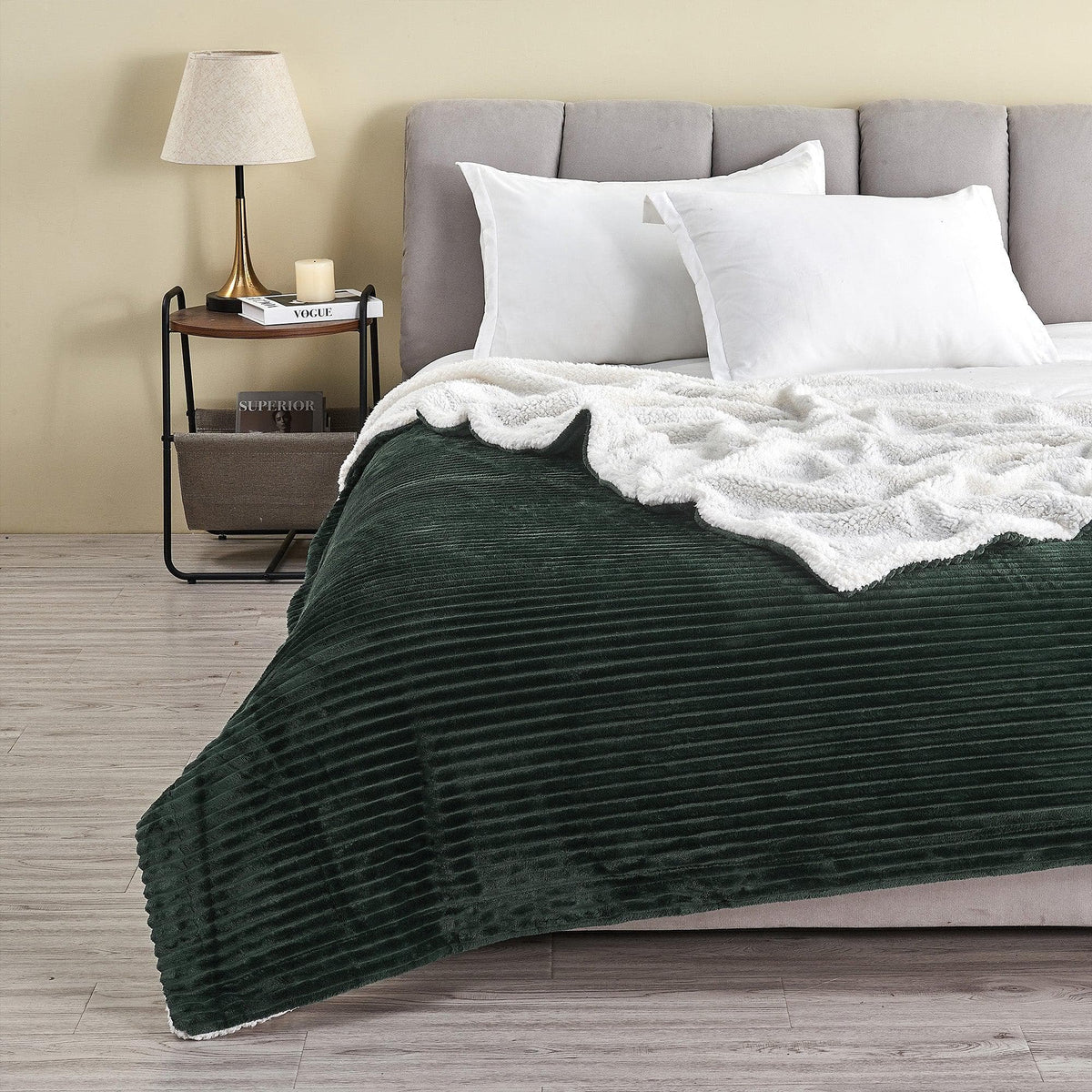 Forest Green ribbed sherpa blanket spread across a bed with its pale reverse folded back; pillows and furnishings are not included.