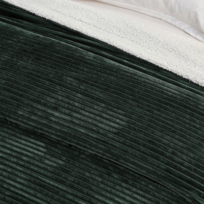 Close-up of the forest green ribbed face and pale sherpa reverse of the blanket.