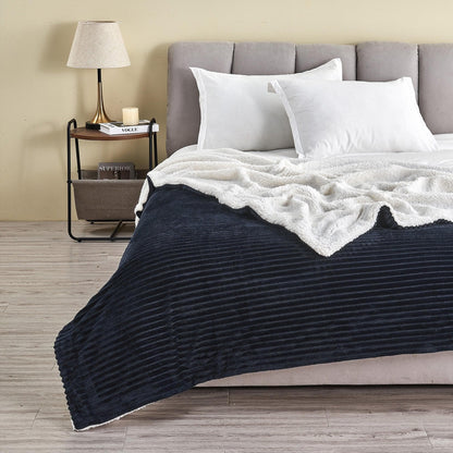 Navy ribbed sherpa blanket spread across a bed with its pale reverse folded back; pillows and furnishings are not included.