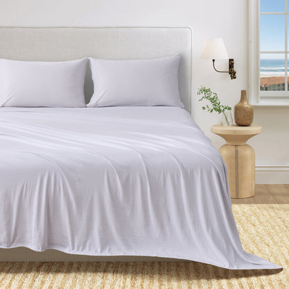 Fog Grey cotton jersey knit sheet set shown on a bed with matching pillowcases in a bright bedroom.