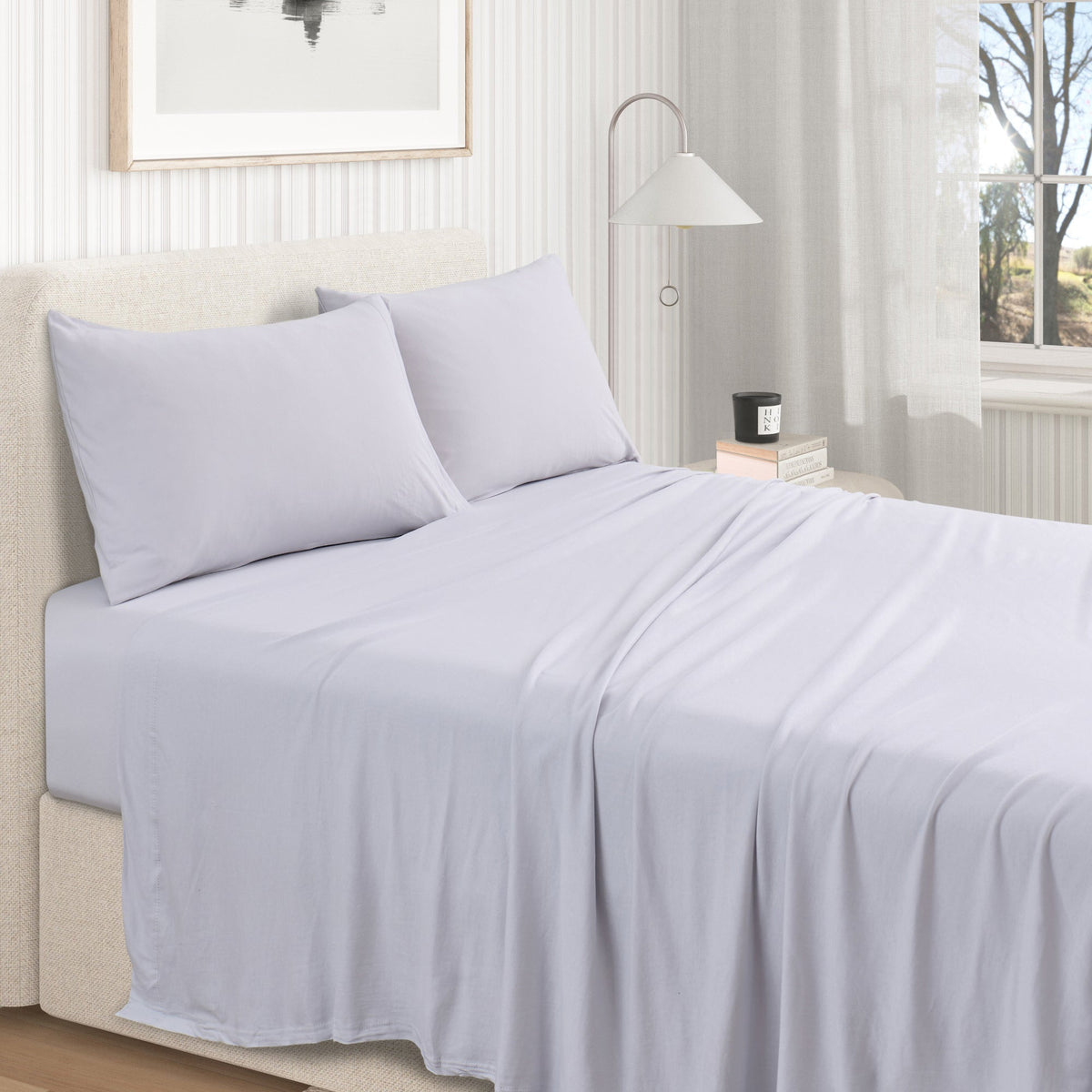 Fog Grey cotton jersey knit sheet set shown on a made bed from a second room angle, with matching pillows and draped sheet.