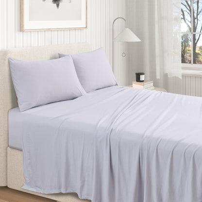 Fog Grey cotton jersey knit sheet set shown on a made bed from a second room angle, with matching pillows and draped sheet.