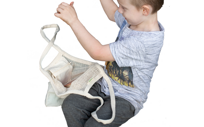 A child holding the cotton mesh tote by its handles to show the bag in use.
