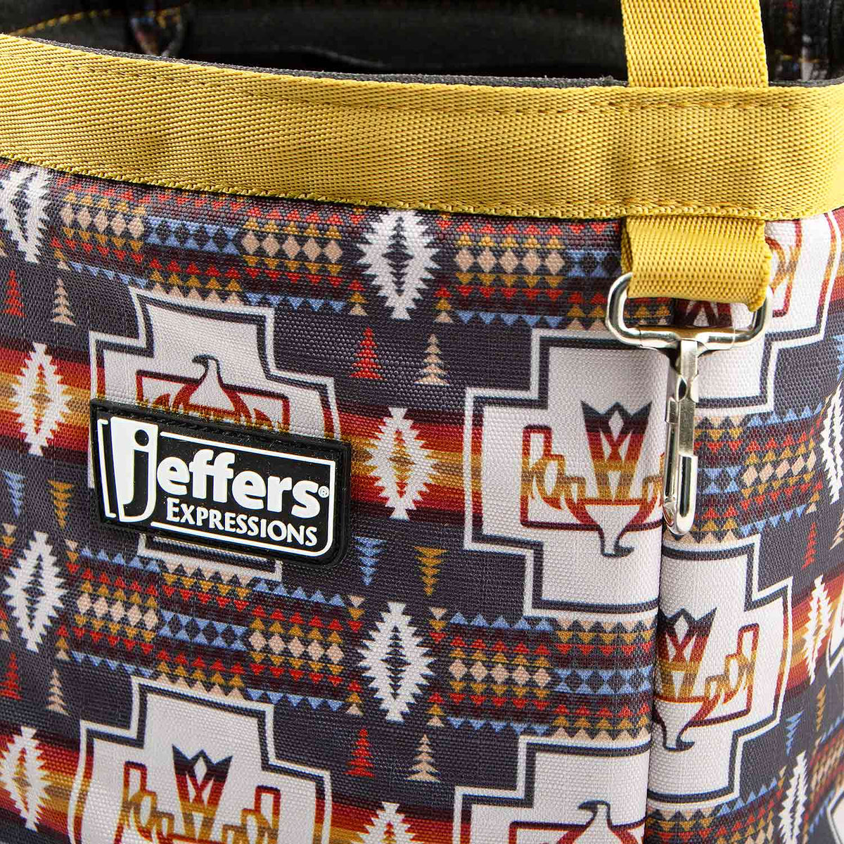 Close-up of the Thunderbird tote's geometric horse pattern, golden-yellow trim, Jeffers patch, and metal clip.