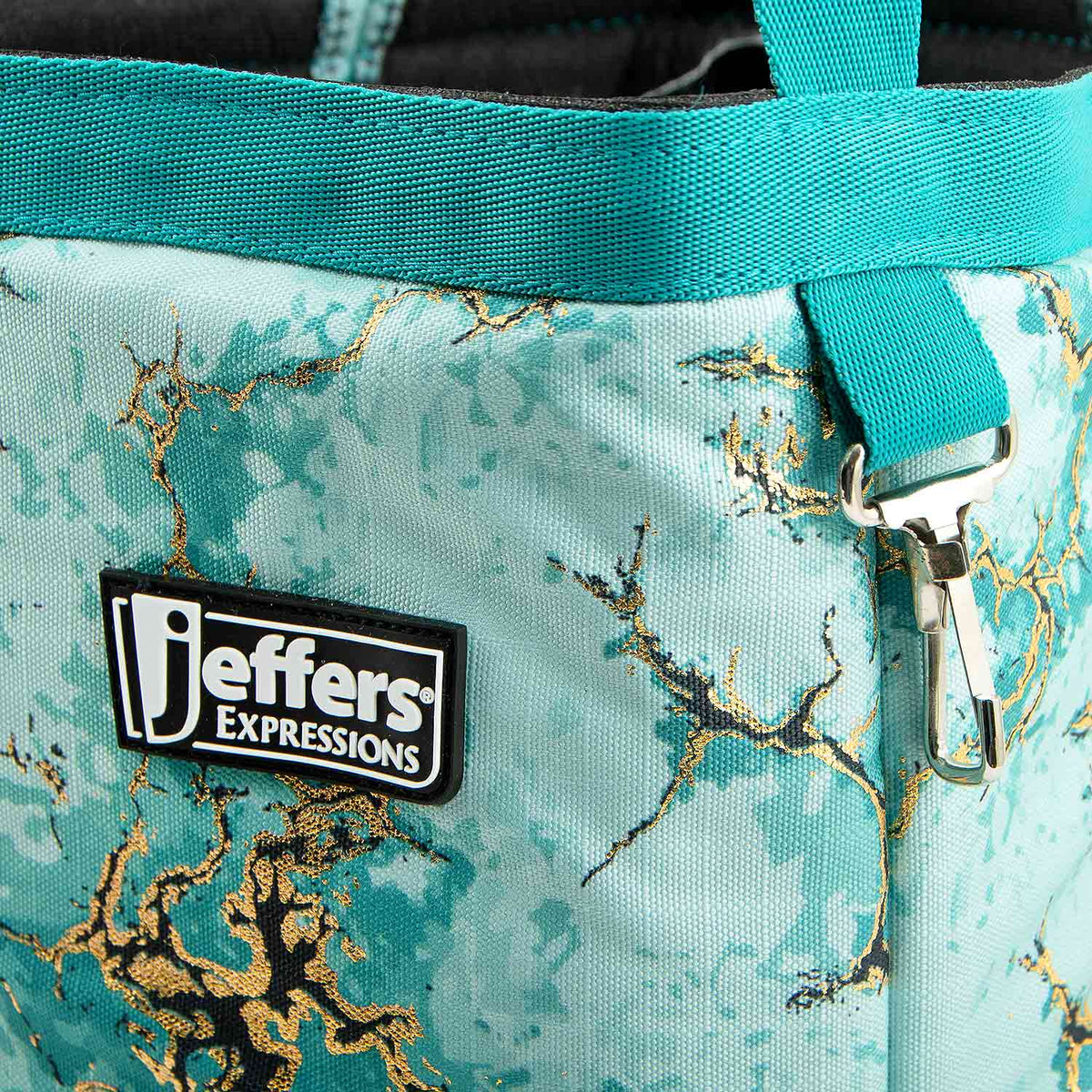Close-up of the Bisbee Blue tote's turquoise marbled print, top trim, Jeffers patch, and metal clip.