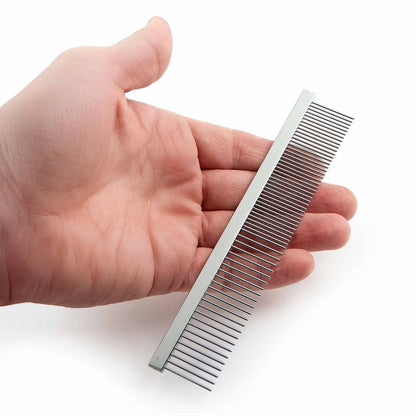 A hand holding one flat-back steel grooming comb.