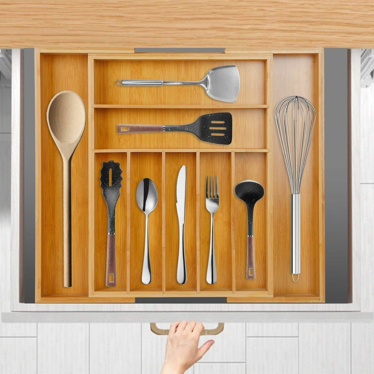 Top view of the bamboo organizer in an open drawer; utensils, hand, drawer and cabinetry are not included.