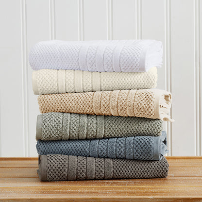 Folded Giuliana Collection towels shown in White, Ivory, Sandstone, Eucalyptus, Blue, and Dark Grey color options; this image shows color choices, not the contents of one set.