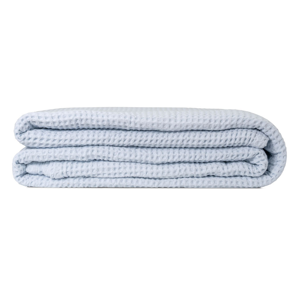 Light blue cotton waffle weave throw folded on a white background