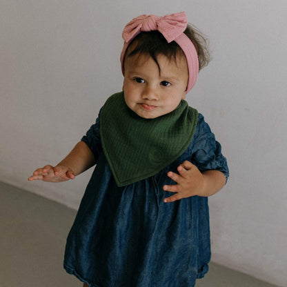 Green Estes muslin bandana bib worn by a baby; clothing and headband not included.