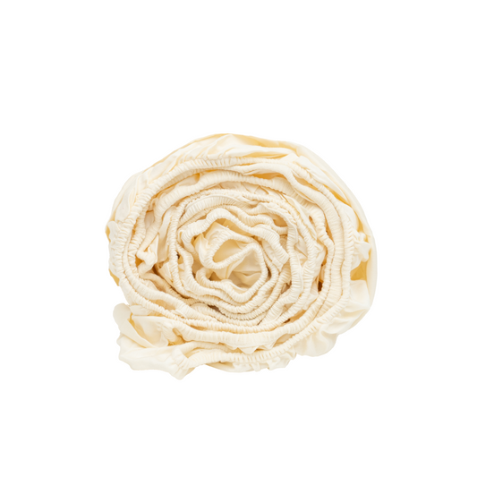 Natural-colour sateen fitted sheet rolled with its elasticated edge visible