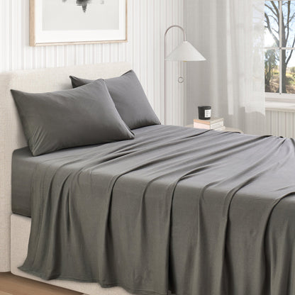 Olive Green cotton jersey knit sheet set shown on a made bed from a second room angle, with matching pillows and draped sheet.