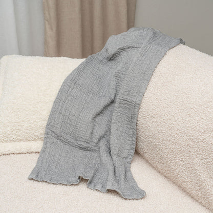 Gray cotton muslin towel draped over a cream sofa; sofa is not included.