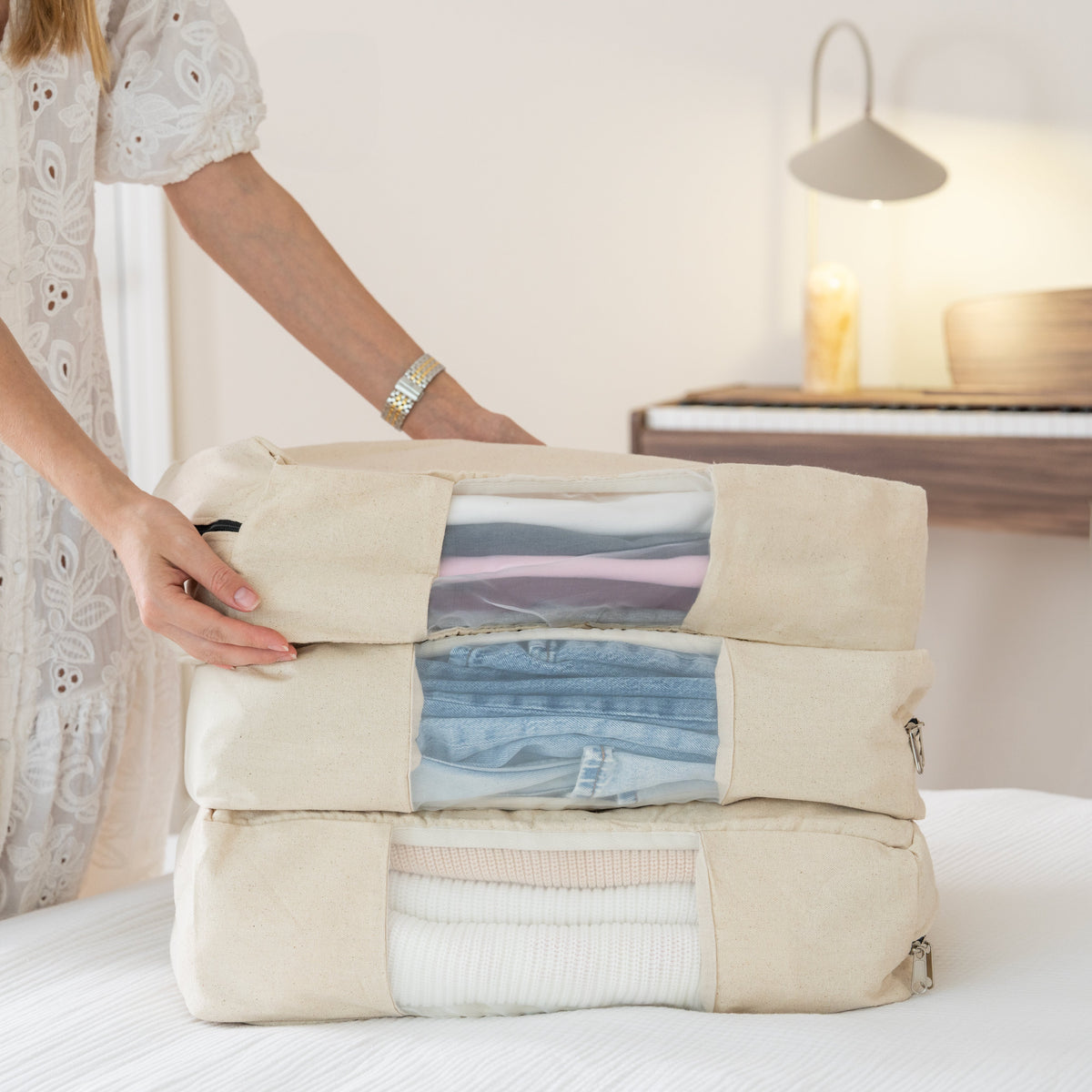 Three garment-storage bags stacked with folded clothing inside