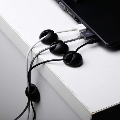 Black cable holders guiding cables beside a laptop; cables and laptop not included