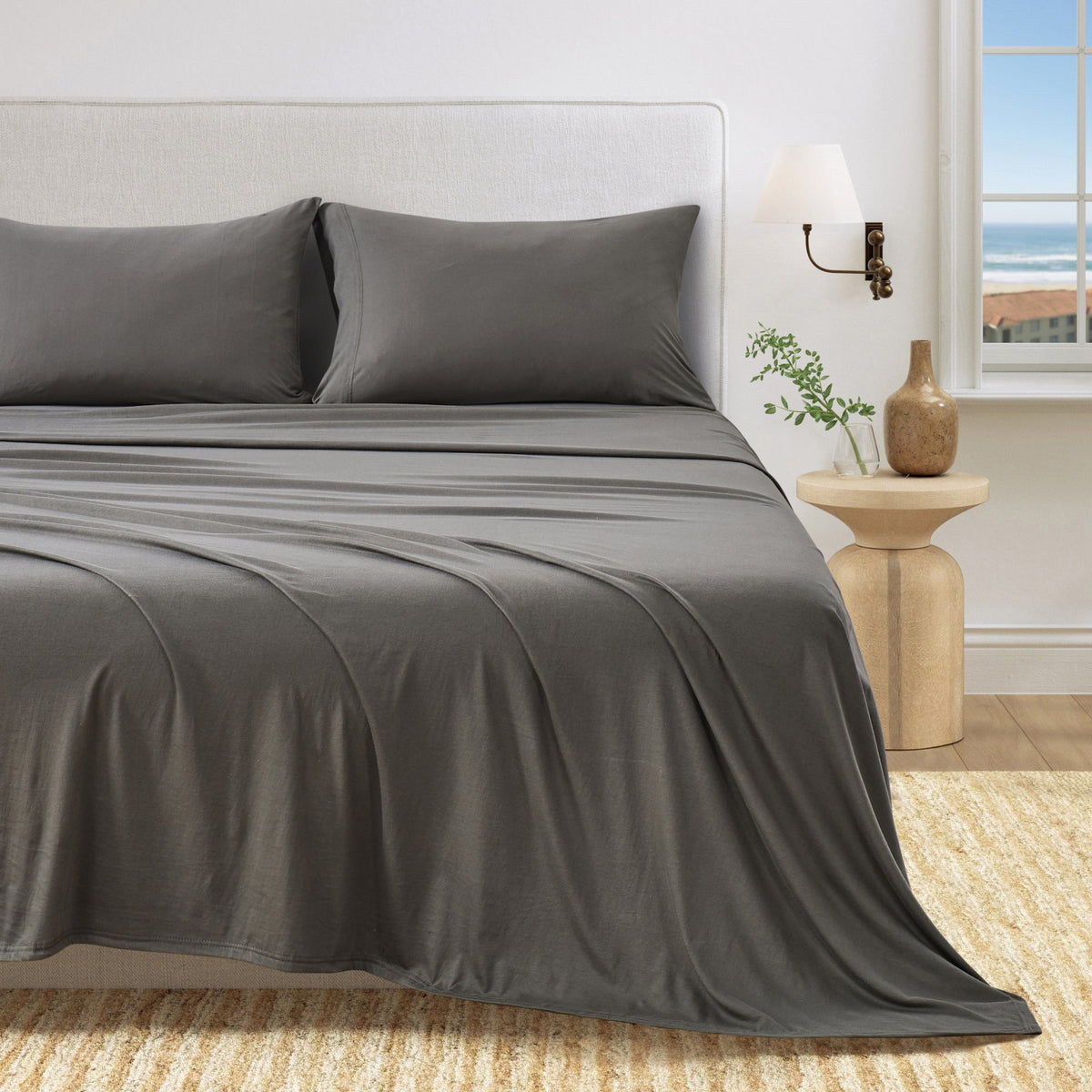 Olive Green cotton jersey knit sheet set shown on a bed with matching pillowcases in a bright bedroom.