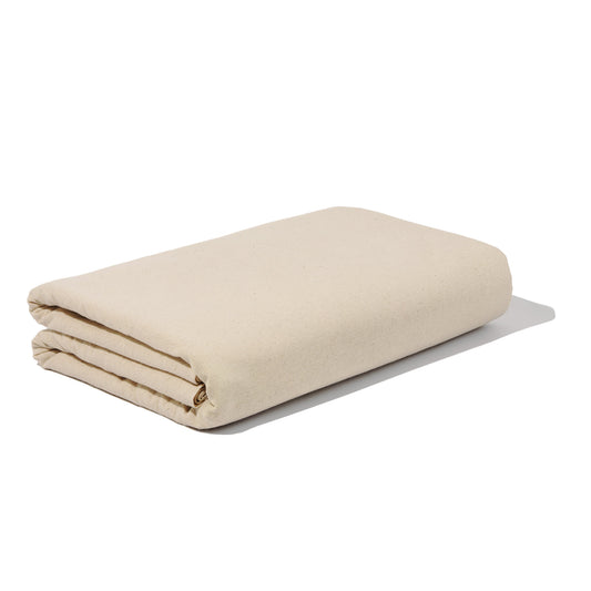 Folded unbleached cotton muslin fabric in a natural cream colour on a white background.